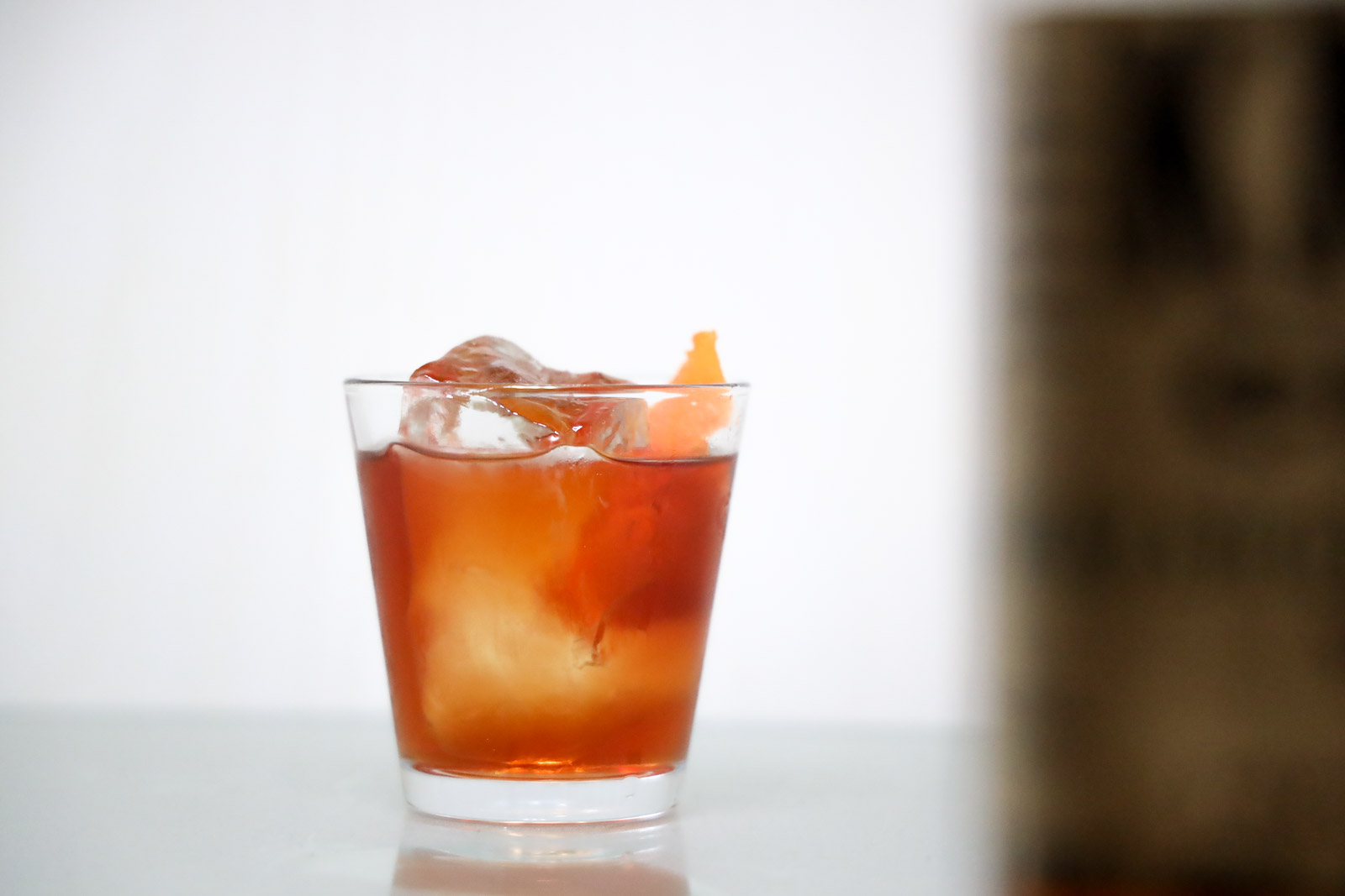 An old fashioned in a lowball glass with a large ice cube and an orange  peel